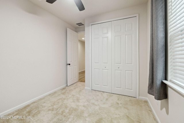 unfurnished bedroom featuring ceiling fan, light colored carpet, and a closet