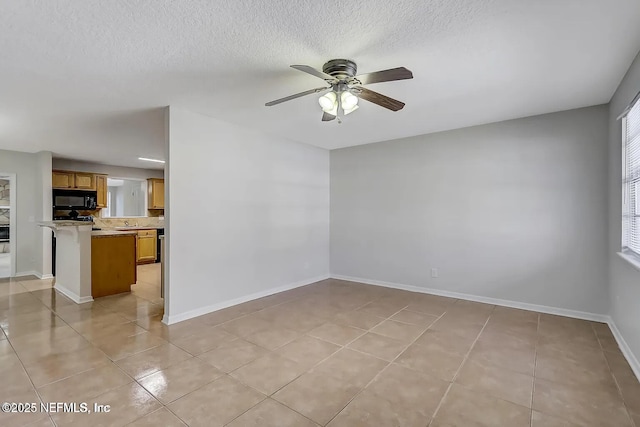 empty room featuring ceiling fan, a textured ceiling, and light tile patterned floors