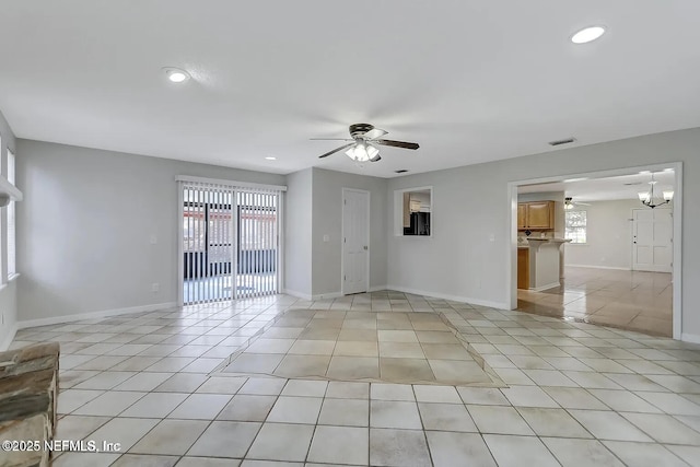 tiled empty room featuring ceiling fan with notable chandelier