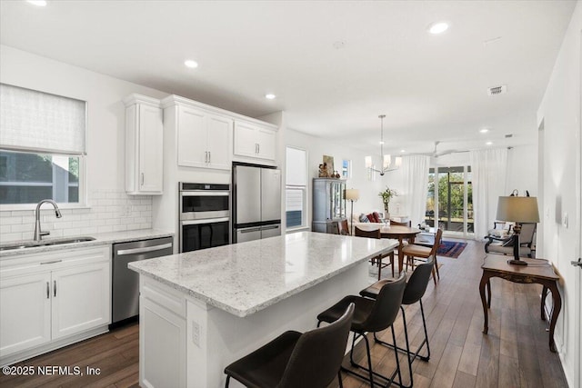 kitchen featuring white cabinetry, sink, pendant lighting, a kitchen island, and appliances with stainless steel finishes