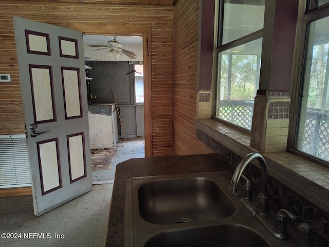 interior space with sink, ceiling fan, and wood walls