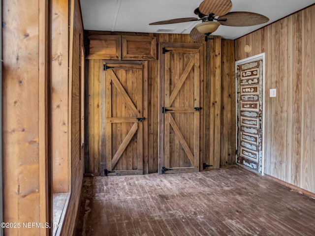 spare room featuring ceiling fan and wooden walls