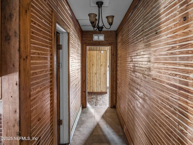 hallway with wood walls, brick wall, and a chandelier