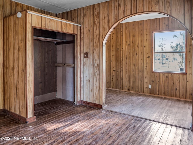 empty room with dark wood-type flooring and wood walls