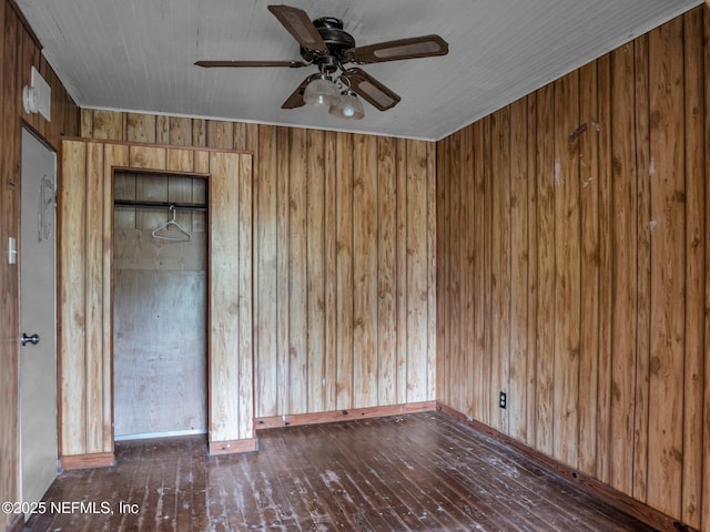 spare room with ceiling fan, dark hardwood / wood-style flooring, and wooden walls