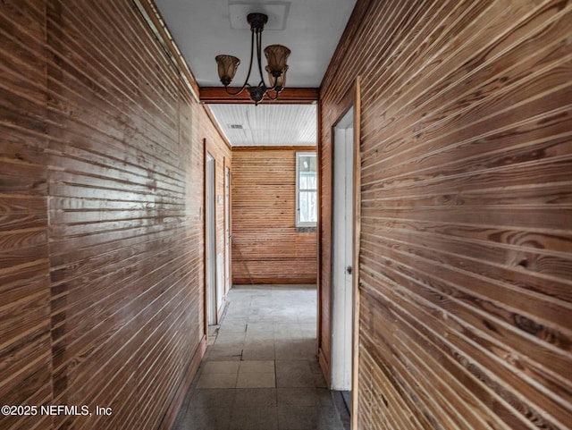 hall featuring ornamental molding, an inviting chandelier, and wooden walls