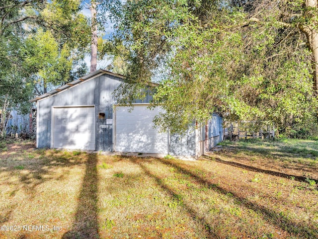 view of side of property featuring a lawn, an outdoor structure, and a garage