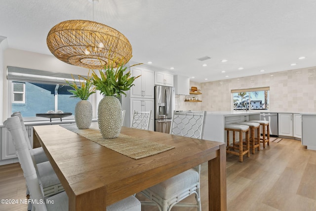 dining space featuring light hardwood / wood-style flooring and a healthy amount of sunlight