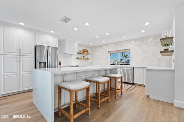 kitchen featuring a breakfast bar, white cabinetry, appliances with stainless steel finishes, and tasteful backsplash