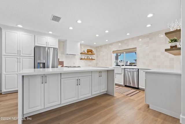 kitchen with backsplash, a center island, white cabinets, and stainless steel appliances