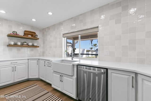 kitchen with decorative backsplash, dark hardwood / wood-style flooring, stainless steel dishwasher, sink, and white cabinets