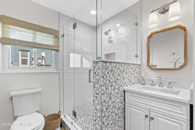 bathroom featuring vanity, toilet, and a shower with shower door