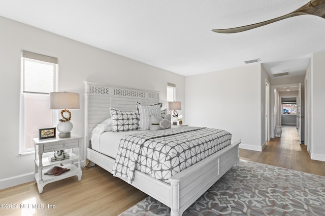 bedroom with multiple windows and hardwood / wood-style flooring