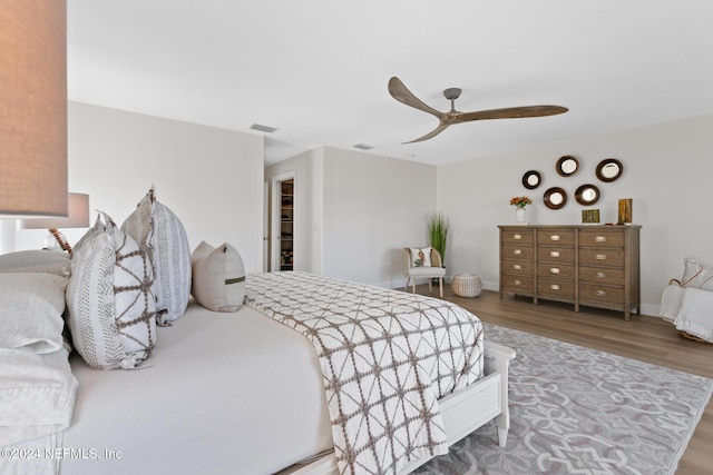 bedroom with hardwood / wood-style floors, a walk in closet, a closet, and ceiling fan