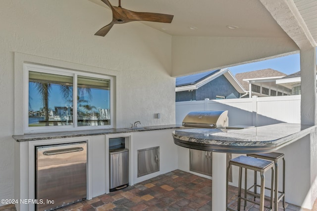 view of patio with area for grilling, ceiling fan, and a wet bar