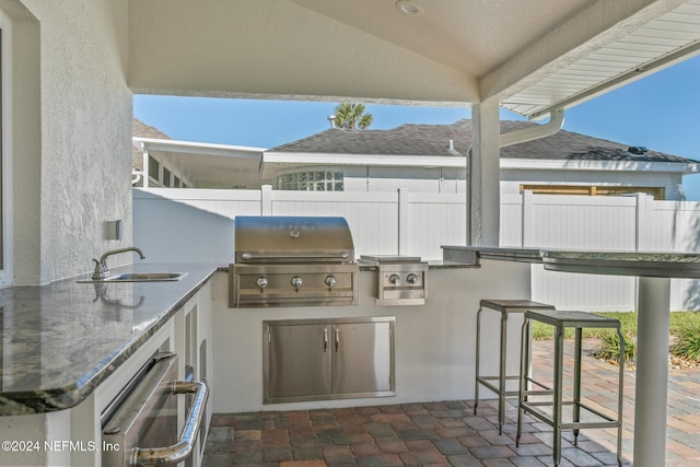 view of patio with grilling area, an outdoor wet bar, and exterior kitchen