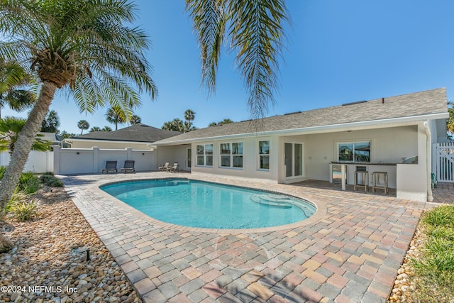 view of pool with an outdoor bar and a patio