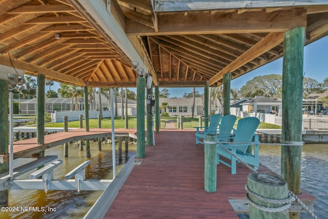 view of dock with a lawn and a water view