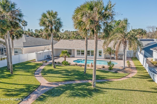 rear view of house with a lawn, a patio area, and a fenced in pool