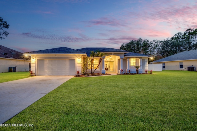 view of front of house with a lawn, central AC unit, and a garage