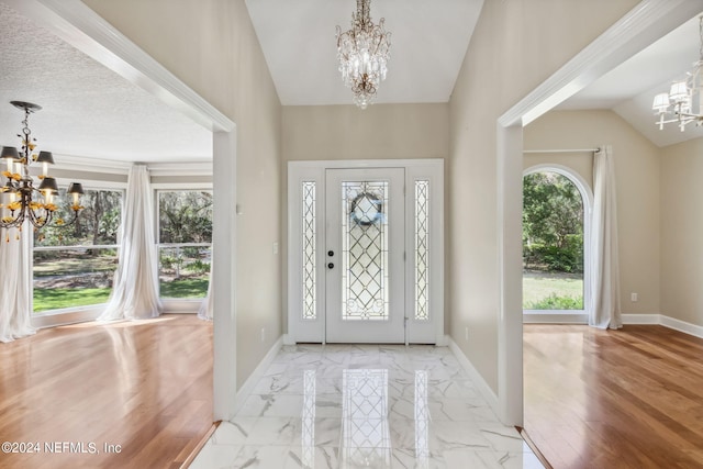 foyer featuring vaulted ceiling, a textured ceiling, and an inviting chandelier