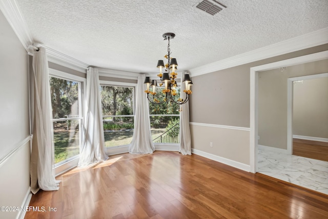 unfurnished dining area with hardwood / wood-style flooring, a textured ceiling, crown molding, and a chandelier