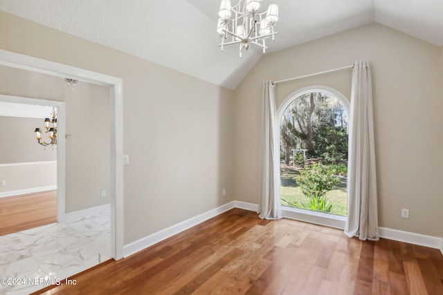 interior space featuring hardwood / wood-style flooring, vaulted ceiling, and a notable chandelier