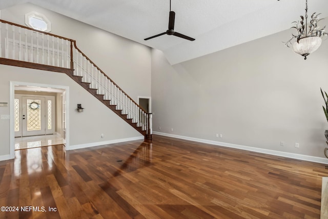 unfurnished living room with dark wood-type flooring and ceiling fan with notable chandelier