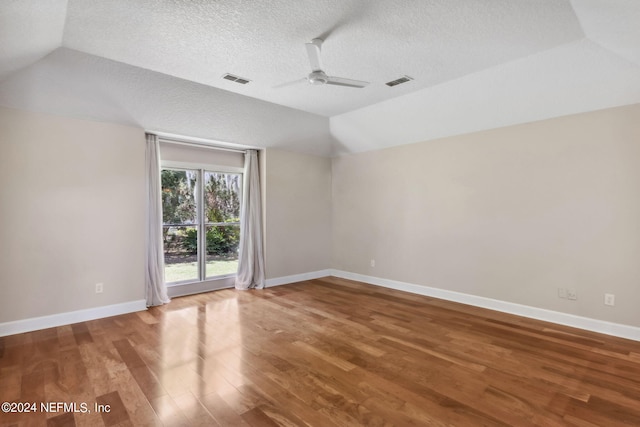 unfurnished room with a textured ceiling, hardwood / wood-style flooring, ceiling fan, and lofted ceiling