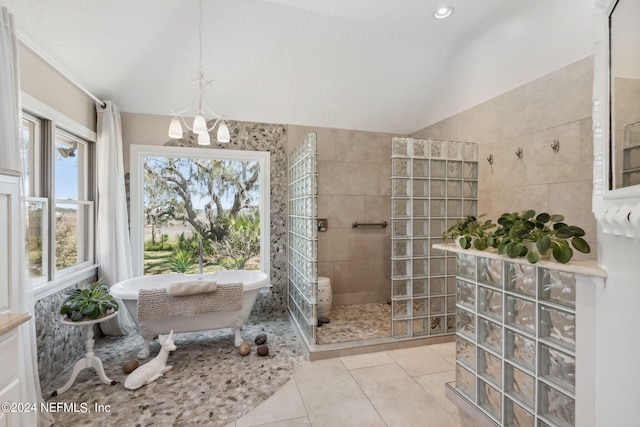 bathroom with a notable chandelier, tile patterned floors, lofted ceiling, independent shower and bath, and tile walls