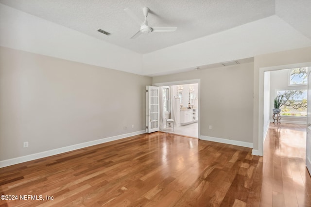 empty room with ceiling fan, wood-type flooring, a textured ceiling, and vaulted ceiling