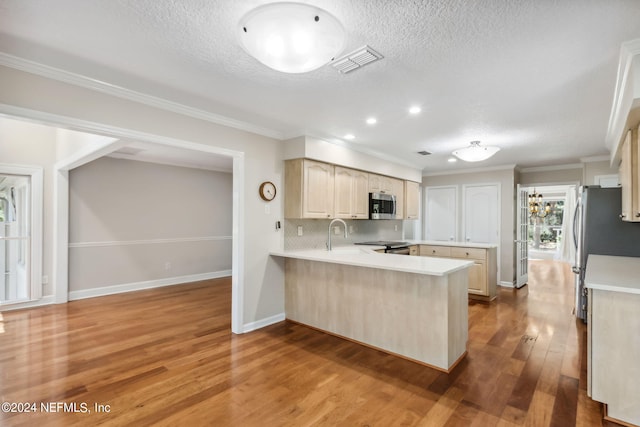 kitchen featuring crown molding, light wood-type flooring, a textured ceiling, appliances with stainless steel finishes, and kitchen peninsula