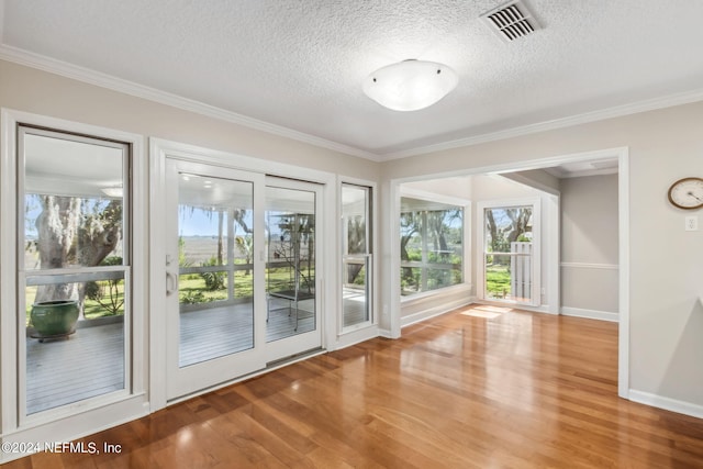 doorway to outside featuring hardwood / wood-style floors, a textured ceiling, and ornamental molding