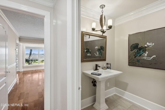 bathroom with a notable chandelier, wood-type flooring, ornamental molding, and a textured ceiling