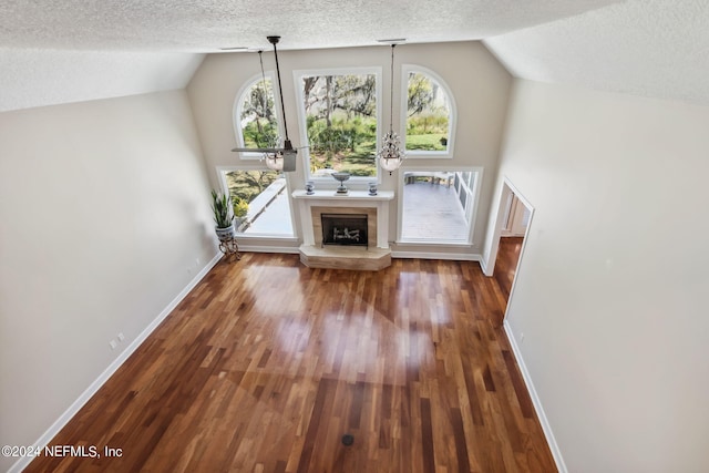 unfurnished living room featuring a textured ceiling, dark wood-type flooring, and lofted ceiling