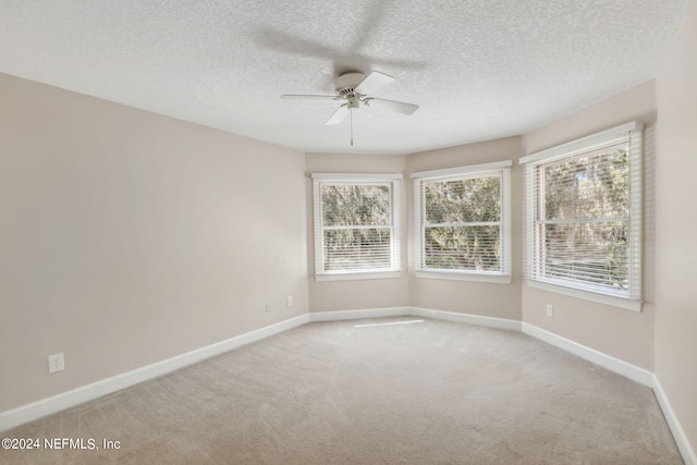 empty room featuring a textured ceiling, light colored carpet, and ceiling fan