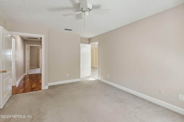 unfurnished bedroom featuring ceiling fan, light colored carpet, and a textured ceiling