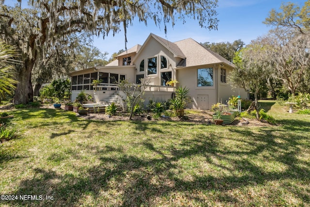 back of property with a lawn and a sunroom