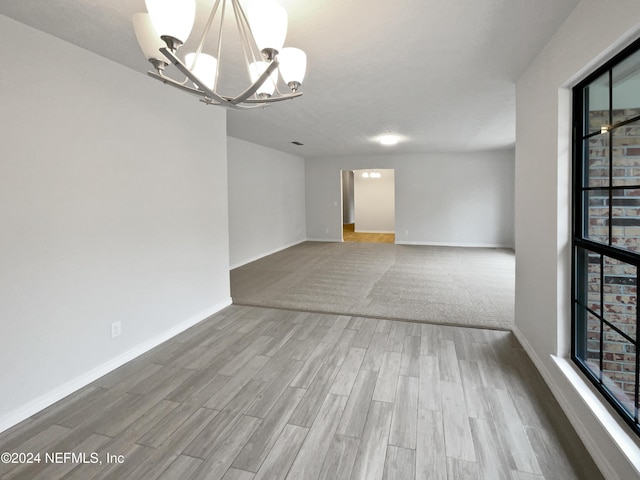 unfurnished room featuring hardwood / wood-style flooring and a notable chandelier