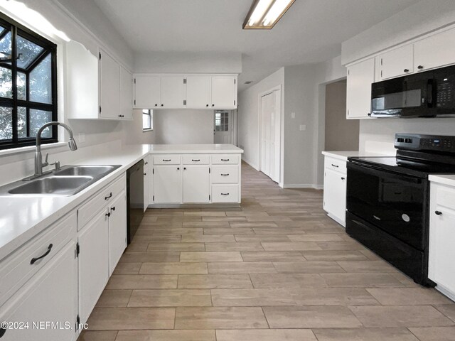 kitchen with black appliances, white cabinets, kitchen peninsula, and sink