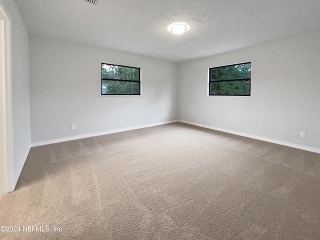 carpeted empty room with a textured ceiling