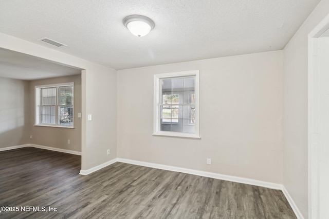 empty room with a textured ceiling and dark hardwood / wood-style flooring