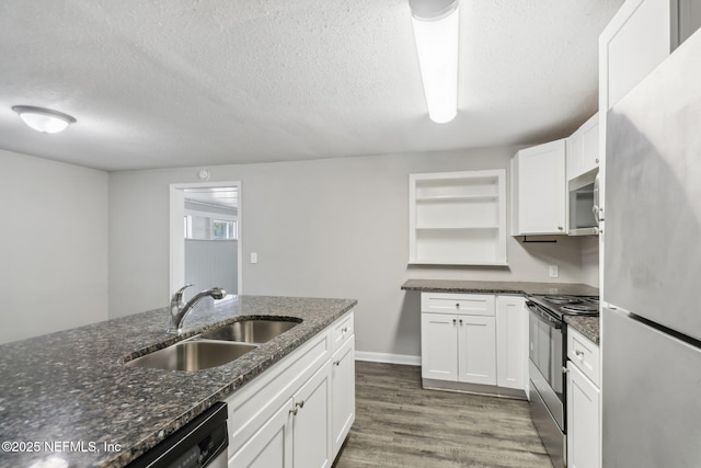 kitchen with stainless steel appliances, white cabinetry, dark stone countertops, and sink