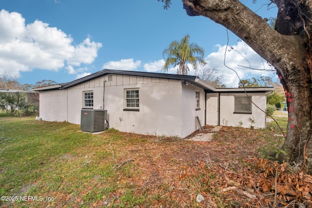 back of property featuring central AC unit and a yard