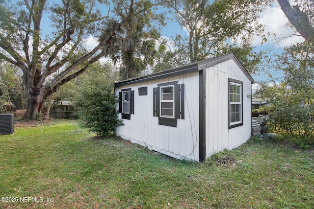 view of outdoor structure with central AC and a yard