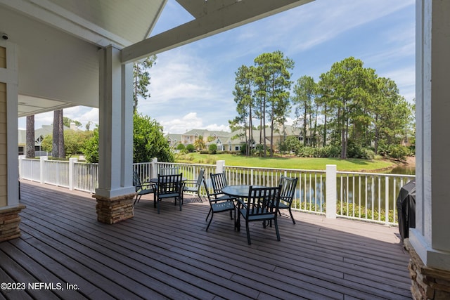 wooden terrace with a water view and a yard