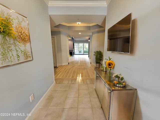 corridor featuring light tile patterned floors, crown molding, and a raised ceiling