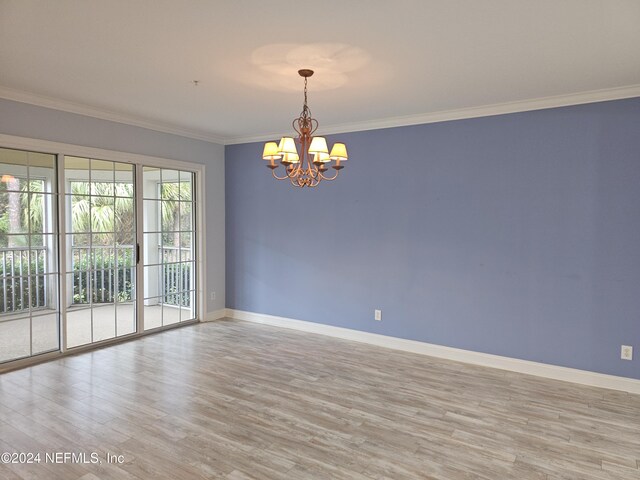 spare room with an inviting chandelier, ornamental molding, and light hardwood / wood-style flooring