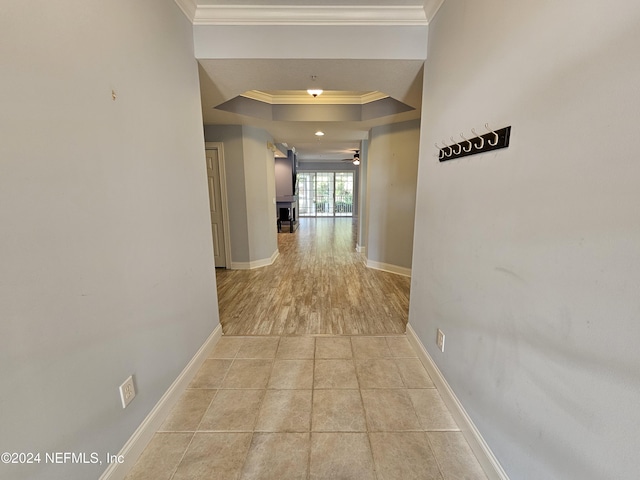 hallway featuring crown molding, light tile patterned floors, and a tray ceiling