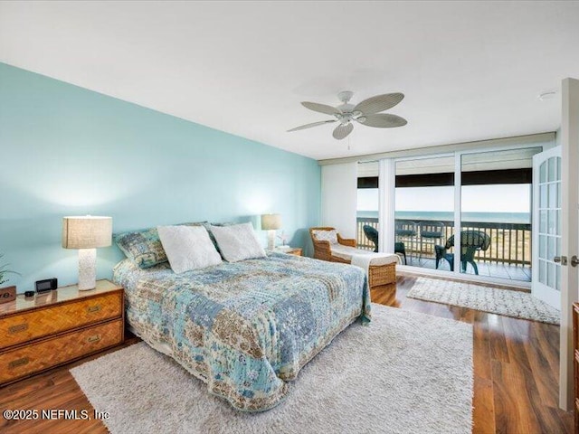 bedroom with floor to ceiling windows, access to exterior, ceiling fan, dark wood-type flooring, and a water view